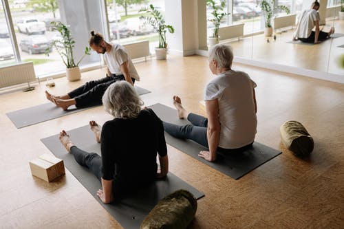 yoga teacher teaching older women streching exercises